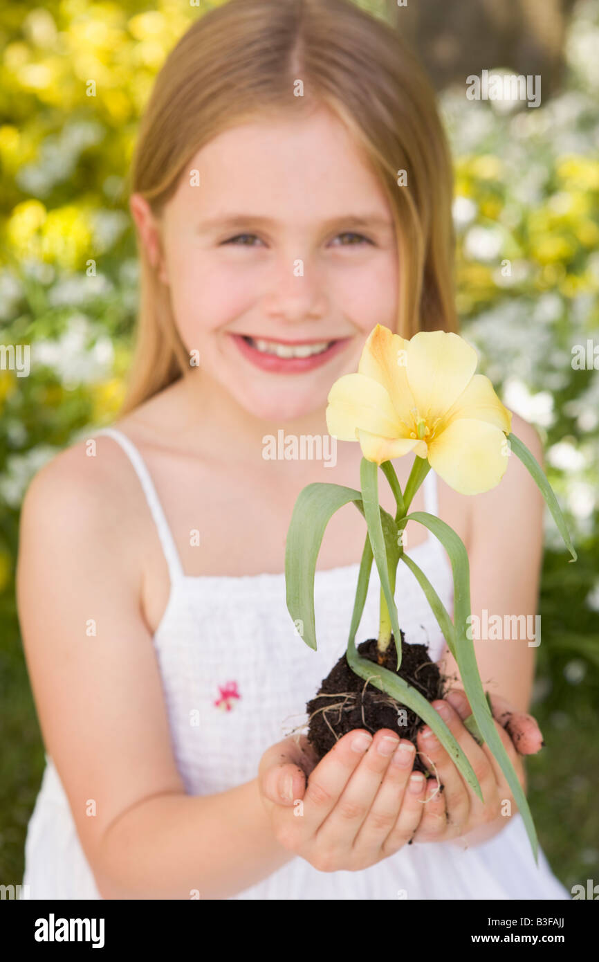 Young girl outdoors holding flower smiling Stock Photo - Alamy