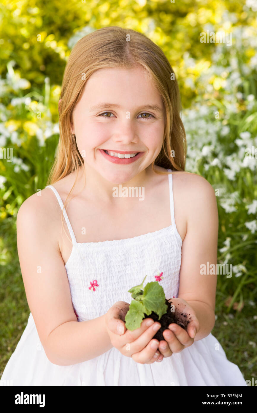 Young girl outdoors holding plant smiling Stock Photo - Alamy