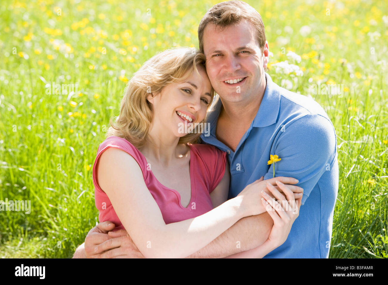 Couple sitting outdoors holding flower smiling Stock Photo - Alamy