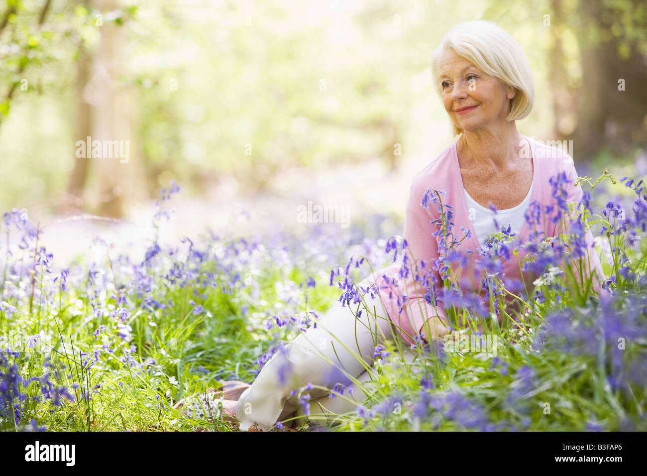 Woman sitting outdoors with flowers smiling Stock Photo - Alamy