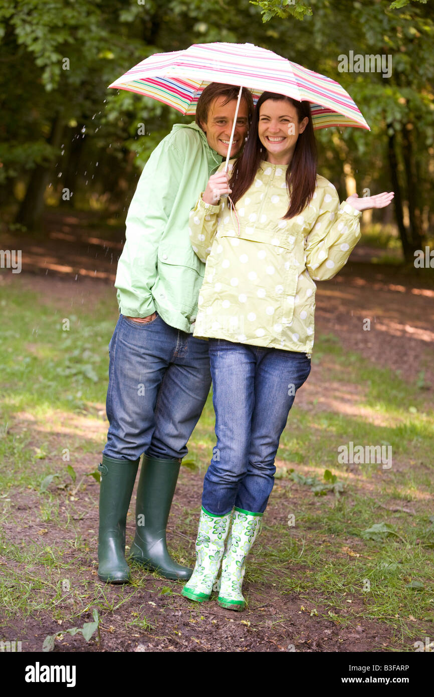 Couple outdoors in rain with umbrella smiling Stock Photo