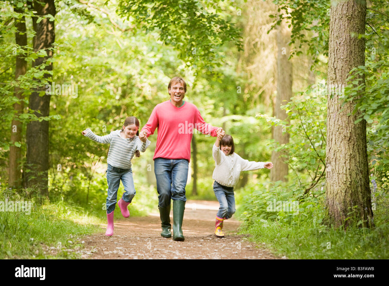 Father and daughters walking on path holding hands smiling Stock Photo ...