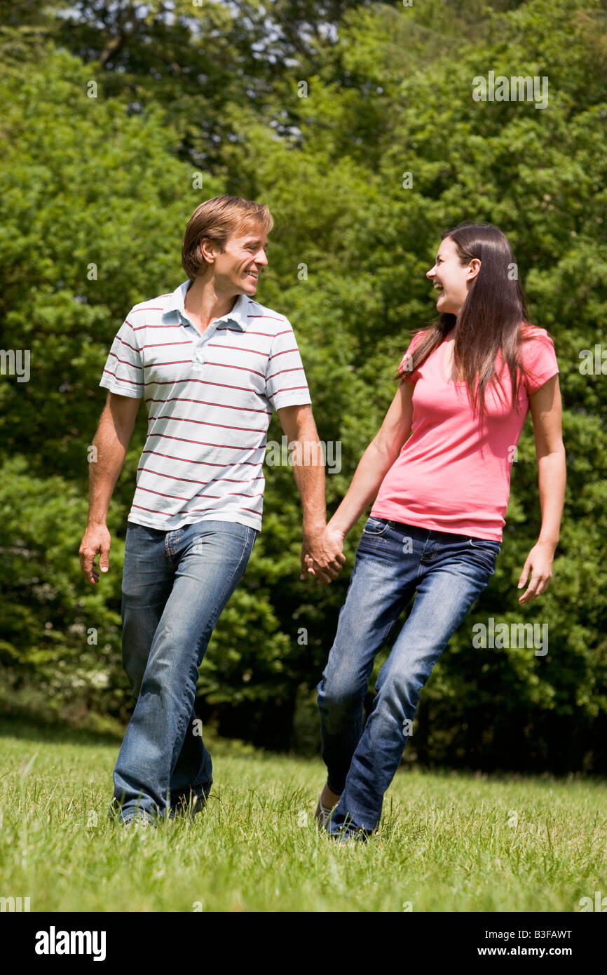 Couple walking outdoors holding hands smiling Stock Photo - Alamy