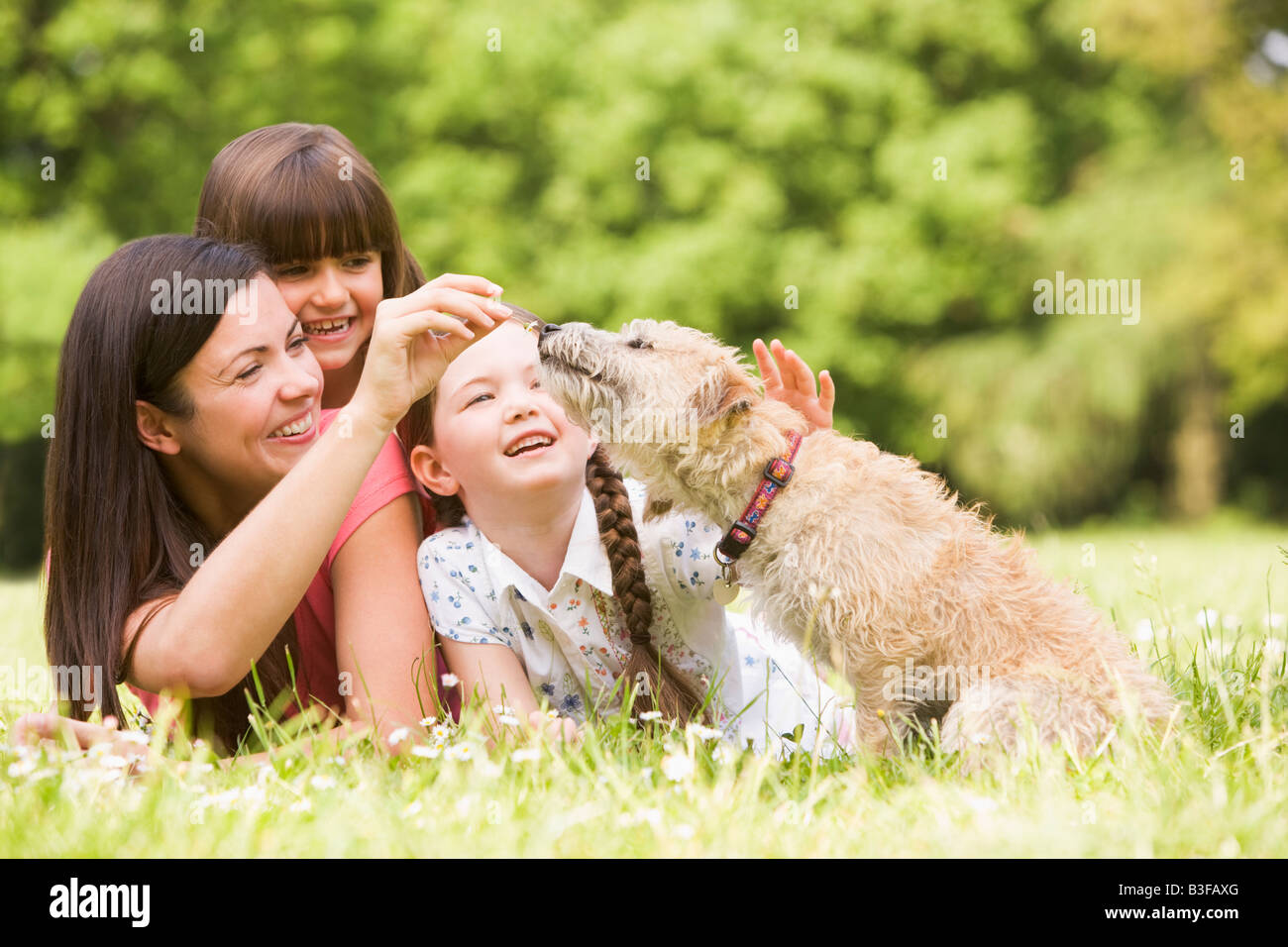 Mother and daughters in park with dog smiling Stock Photo Alamy