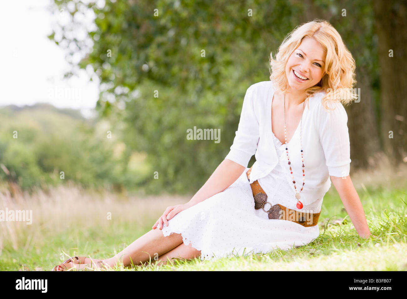 Woman sitting outdoors smiling Stock Photo - Alamy