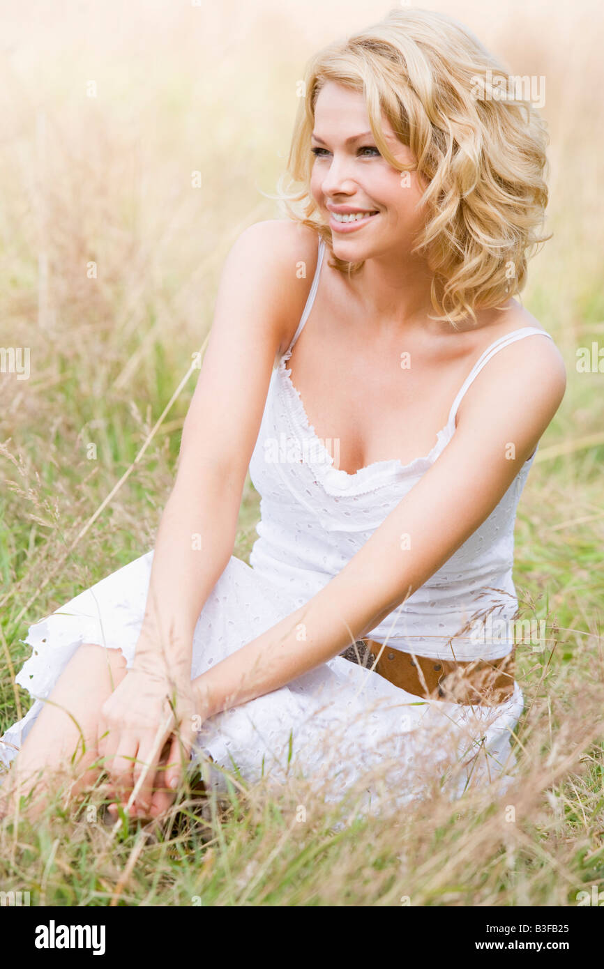 Woman sitting outdoors smiling Stock Photo - Alamy