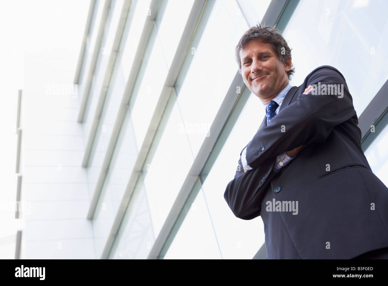Businessman standing outdoors by building smiling Stock Photo - Alamy