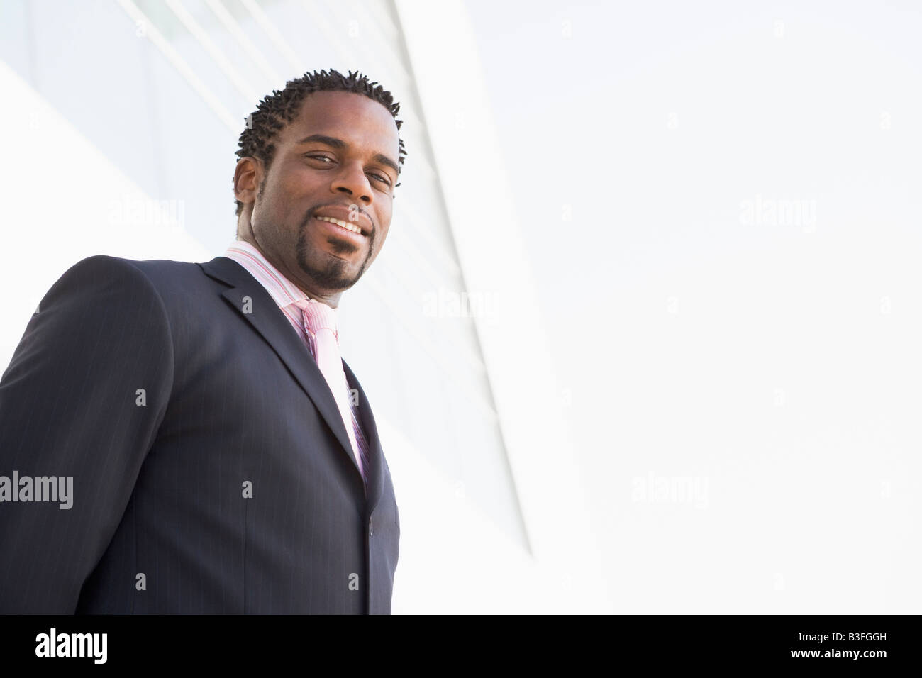 Businessman standing outdoors by building smiling Stock Photo - Alamy