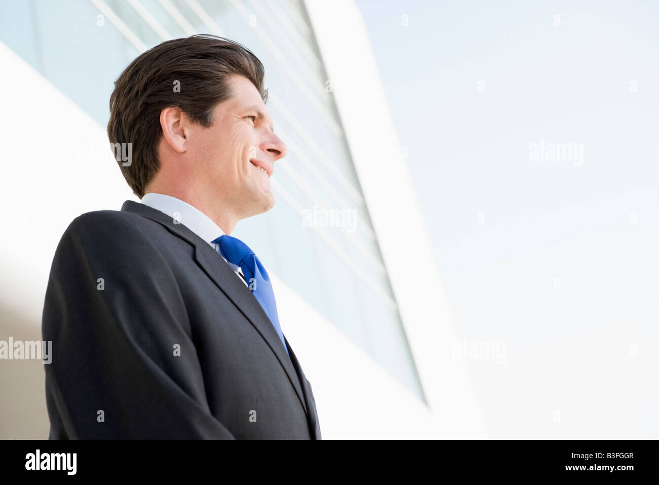 Businessman standing outdoors by building smiling Stock Photo - Alamy