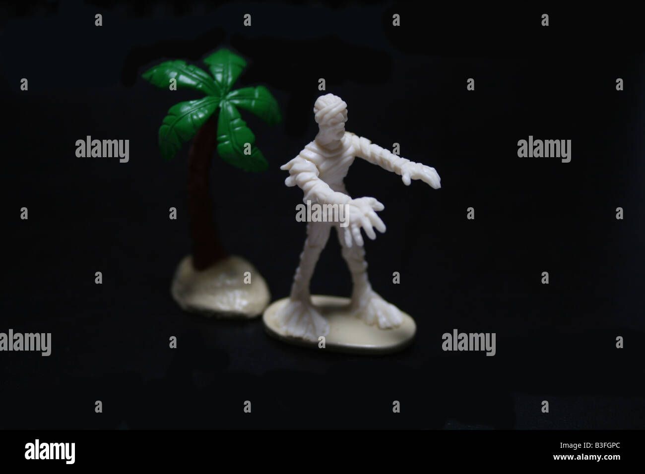 White Egyptian mummy and date palm tree toy statue for Halloween gift or idea for party costume 2009 against black background Stock Photo