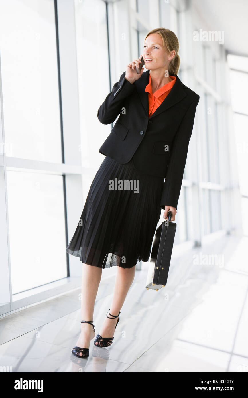 Businesswoman walking in corridor talking on cellular phone Stock Photo