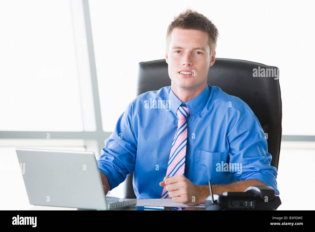 Businessman sitting in office with laptop Stock Photo - Alamy