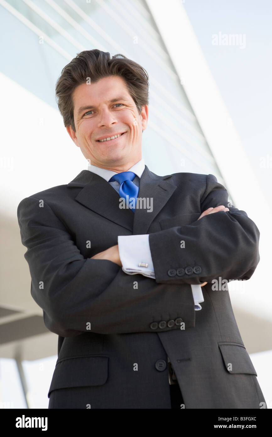 Businessman standing outdoors by building smiling Stock Photo - Alamy