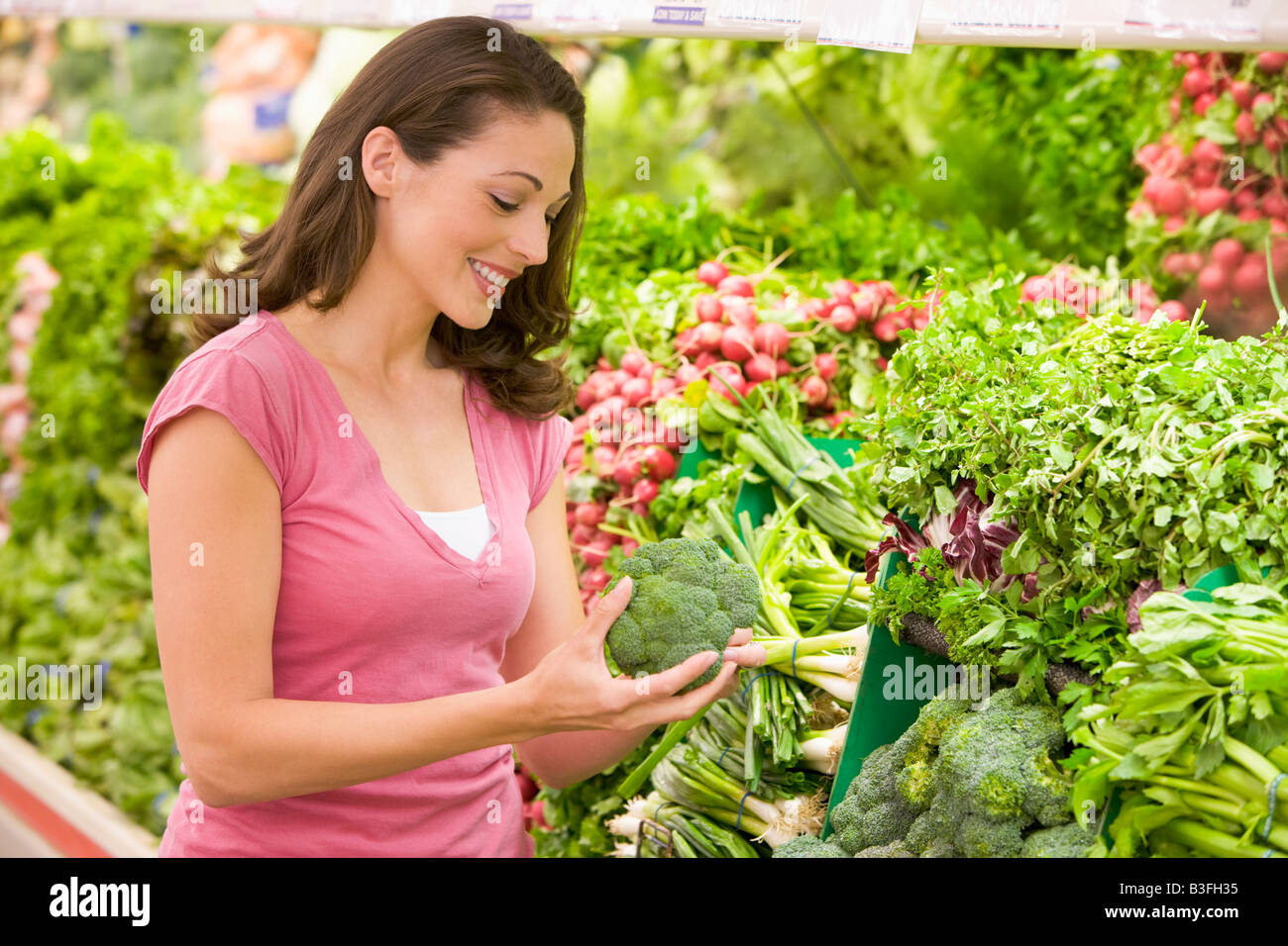 Woman shopping for broccoli at a grocery store Stock Photo