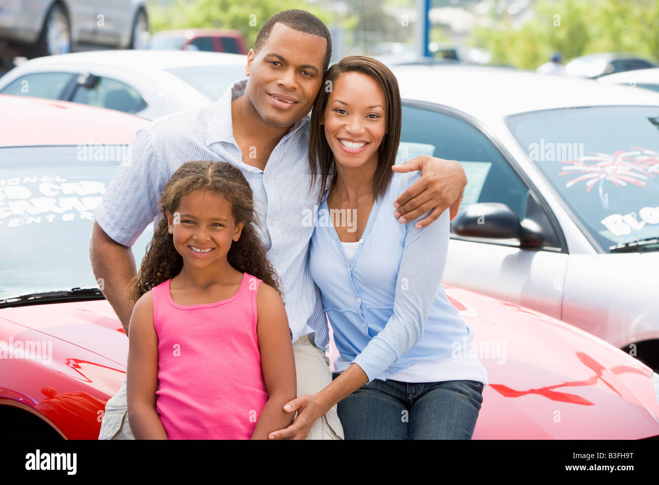 Mother and father with young daughter shopping for a new car Stock