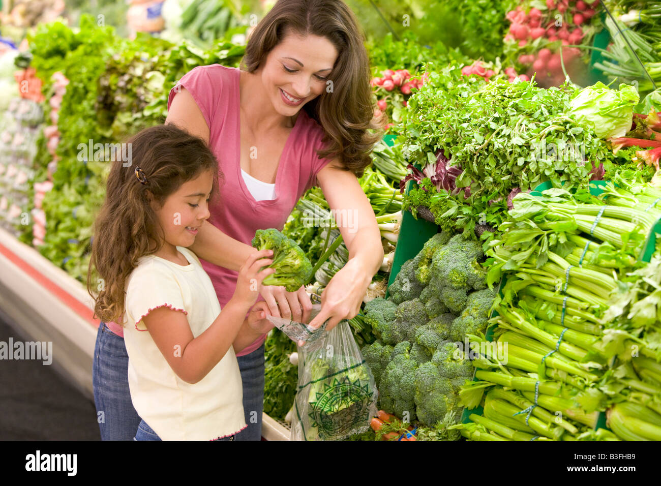 Mother and daughter shopping for broccoli at a grocery store Stock