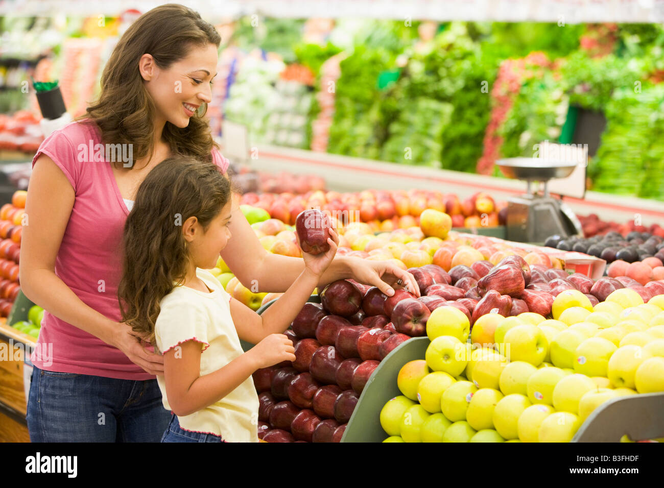 Woman and daughter shopping for apples at a grocery store Stock Photo