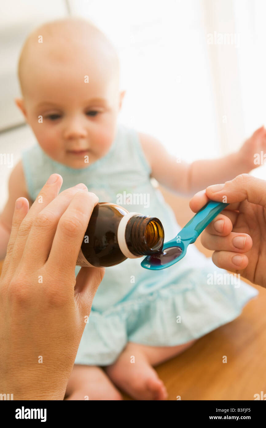 Mother giving baby medicine indoors Stock Photo Alamy