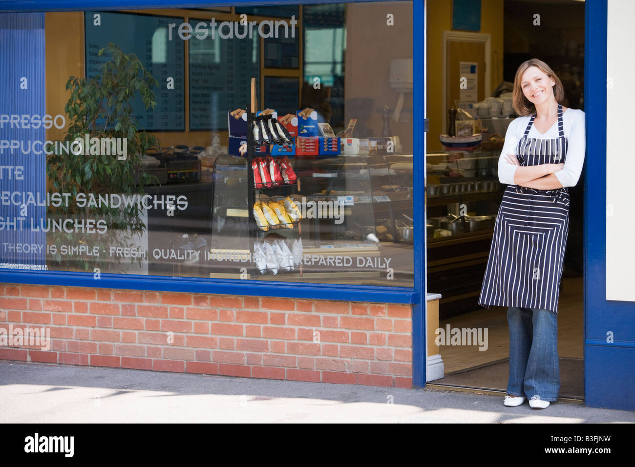 Woman standing in doorway of restaurant smiling Stock Photo - Alamy