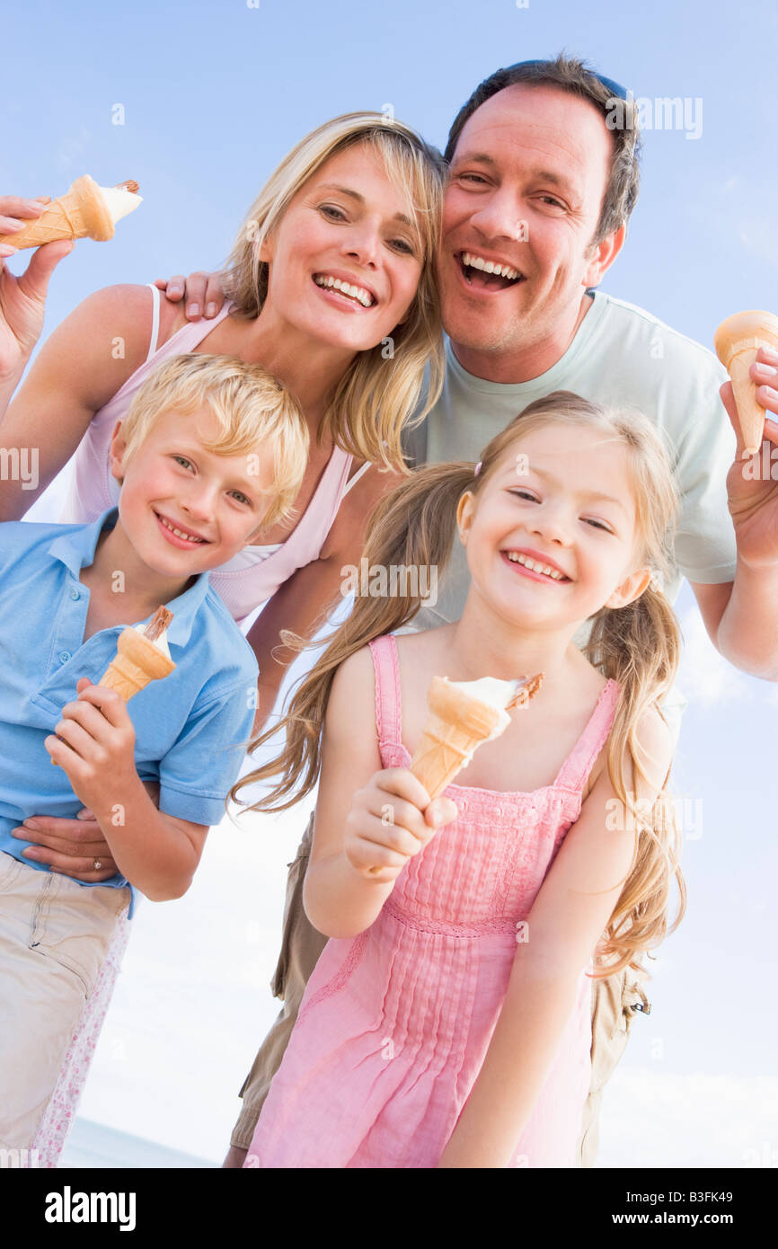 Family standing at beach with ice cream smiling Stock Photo