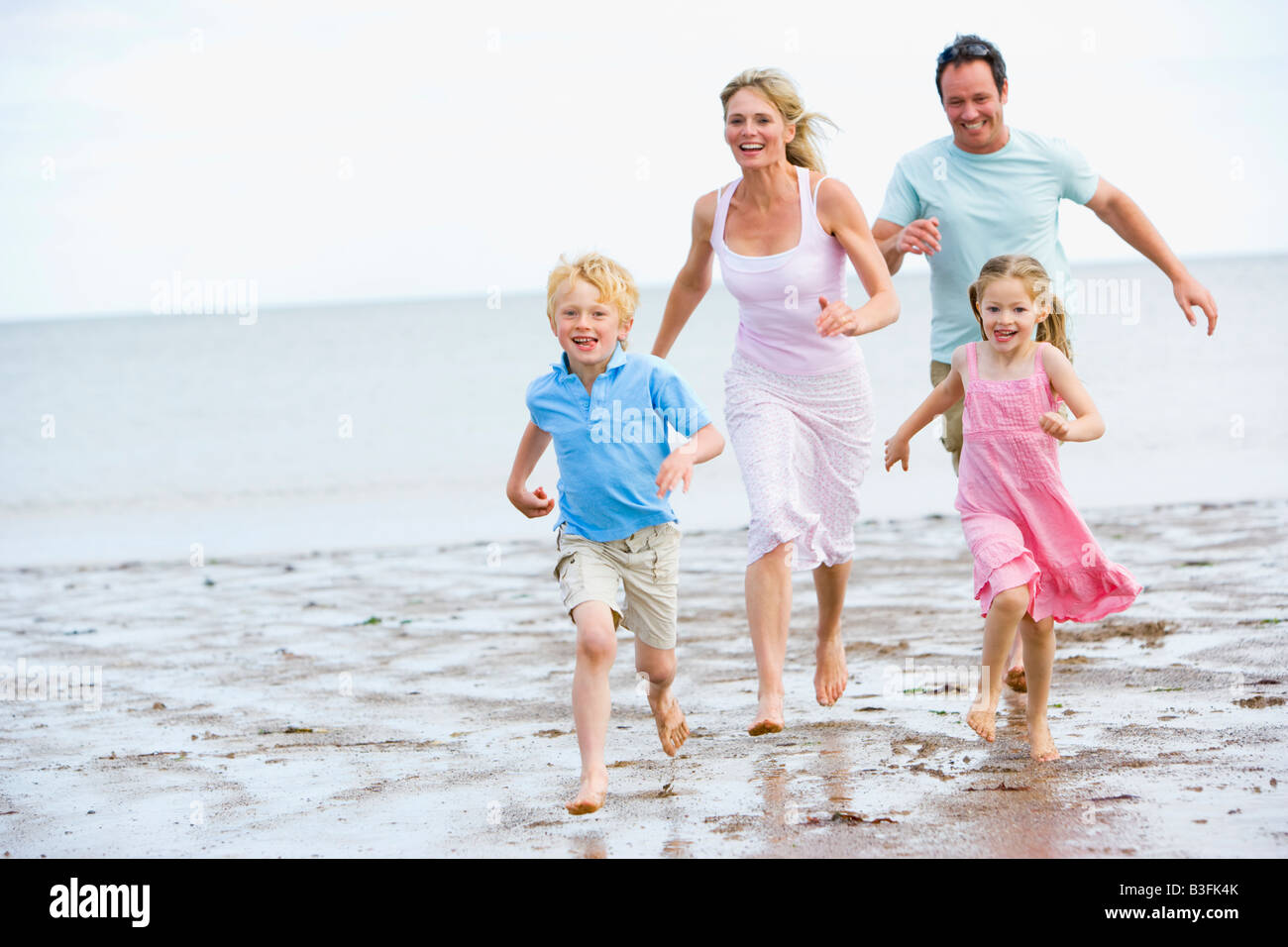 Family running on beach smiling Stock Photo