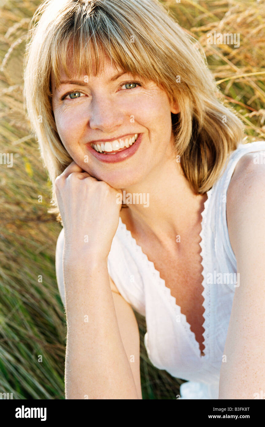 Woman sitting outdoors smiling Stock Photo - Alamy