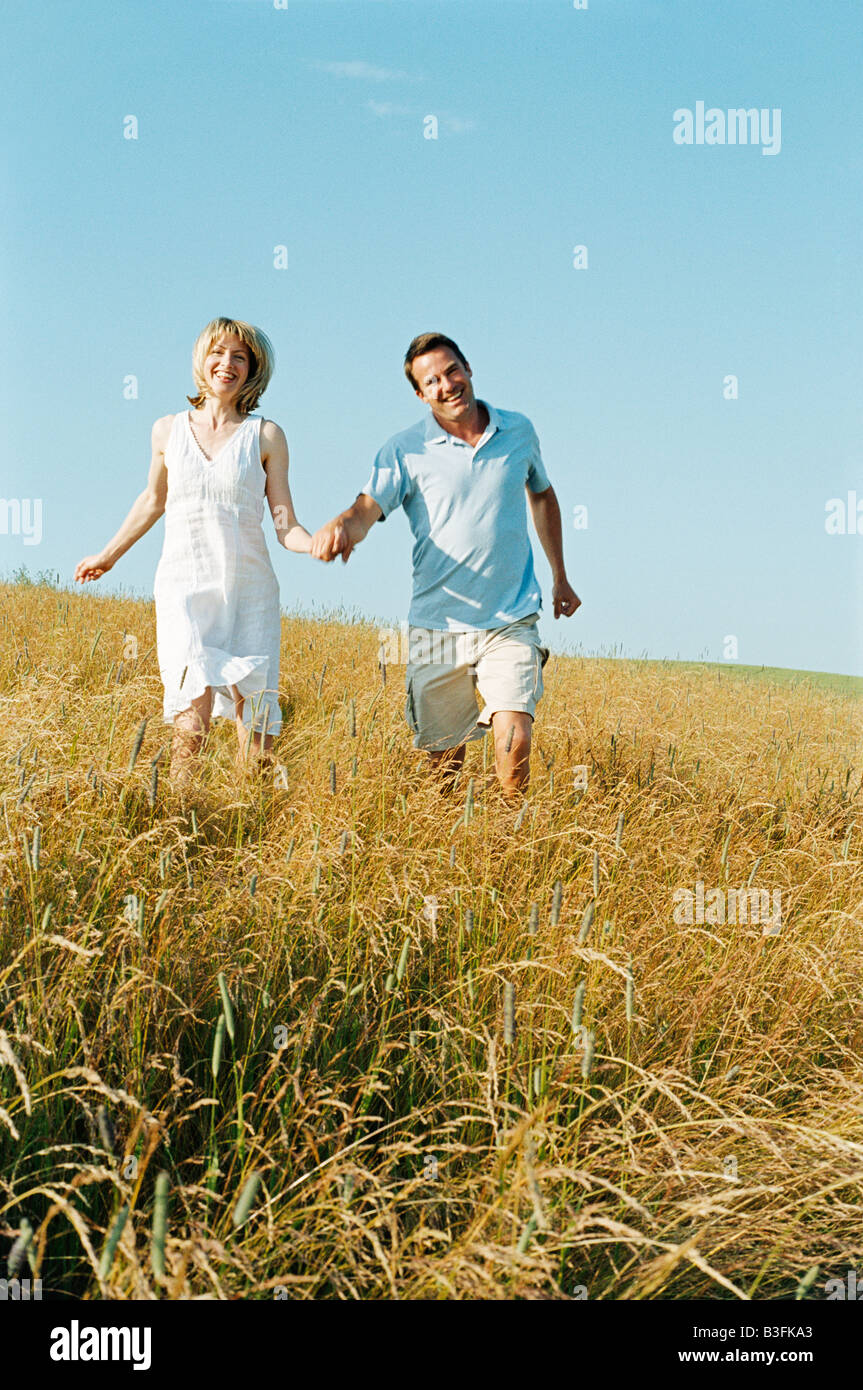 Couple walking outdoors holding hands smiling Stock Photo - Alamy
