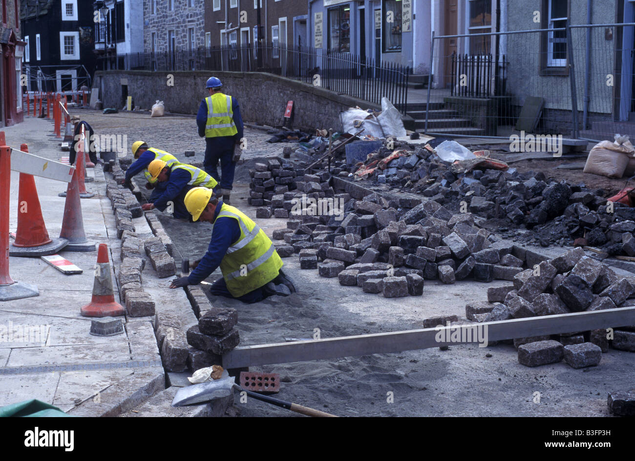 workmen laying cobblestones Stock Photo