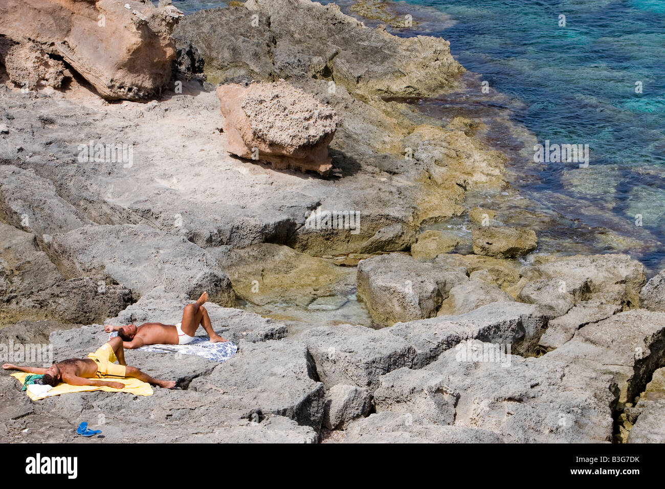 Sunbathers over a rock in Formentera Stock Photo