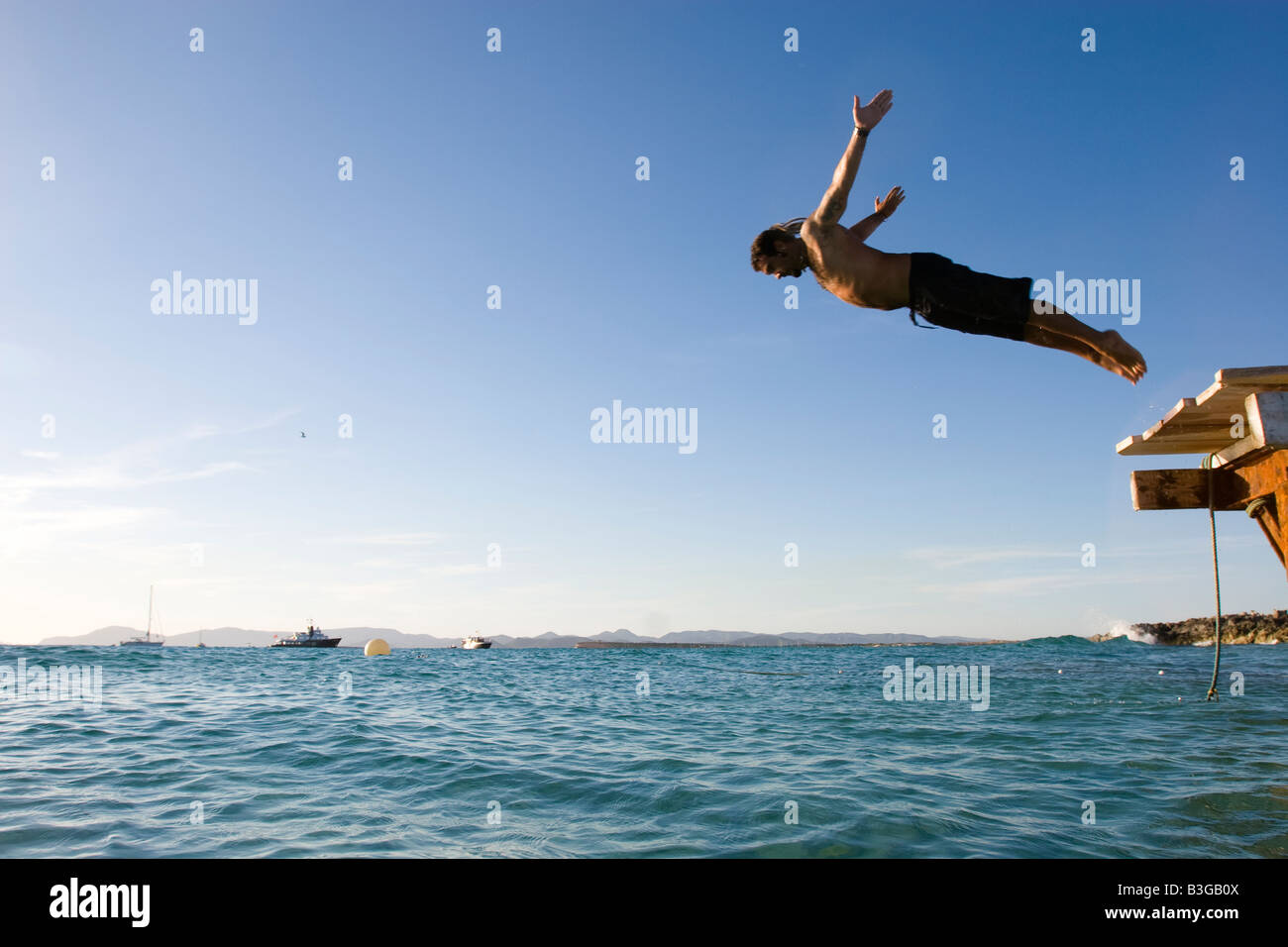 Man jumping from a gangway to the sea Stock Photo