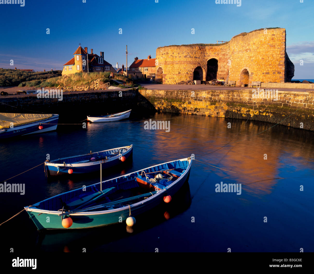 View across the harbour at Beadnell, Northumberland, England, towards the lime kilns in evening sunlight Stock Photo