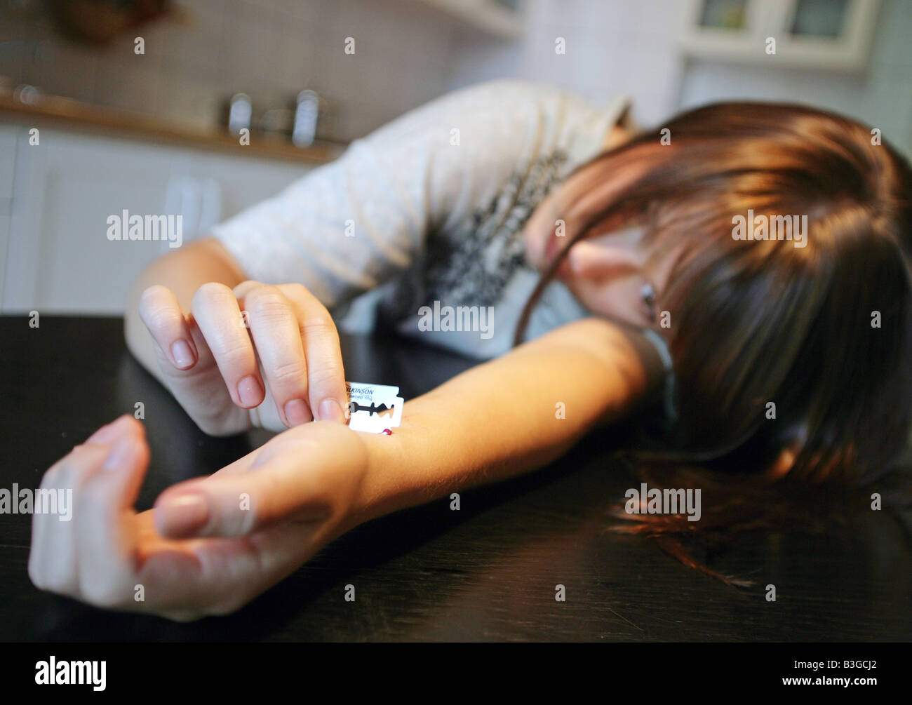 young woman hurts herself with a razor blade Stock Photo