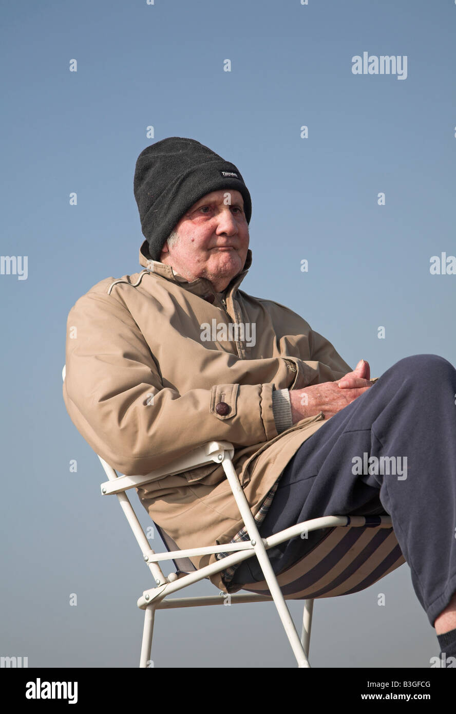 Elderly man sitting on beach in chair Stock Photo - Alamy