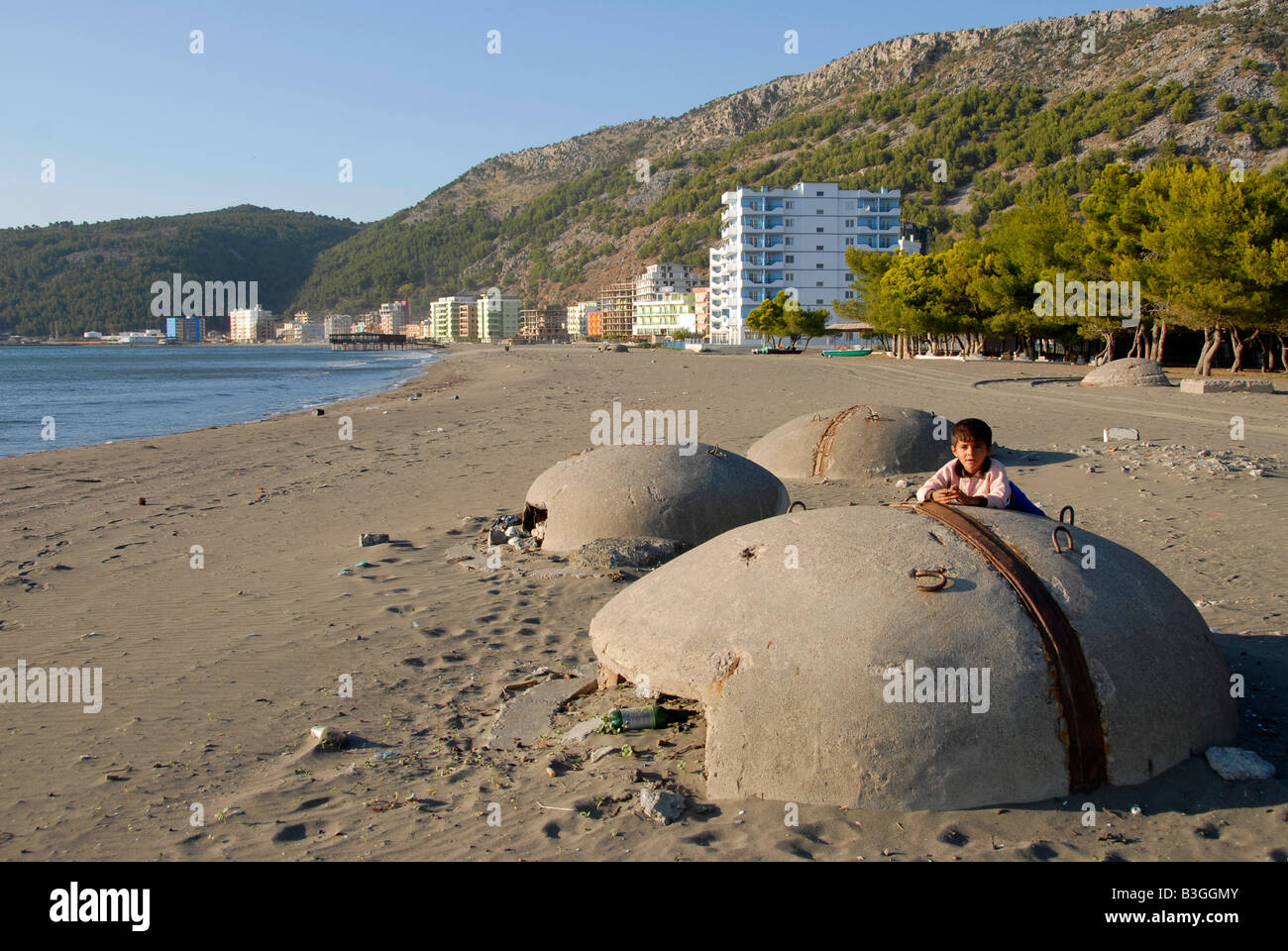 Young boy with abandoned bunkers on the beach, Albania Stock Photo
