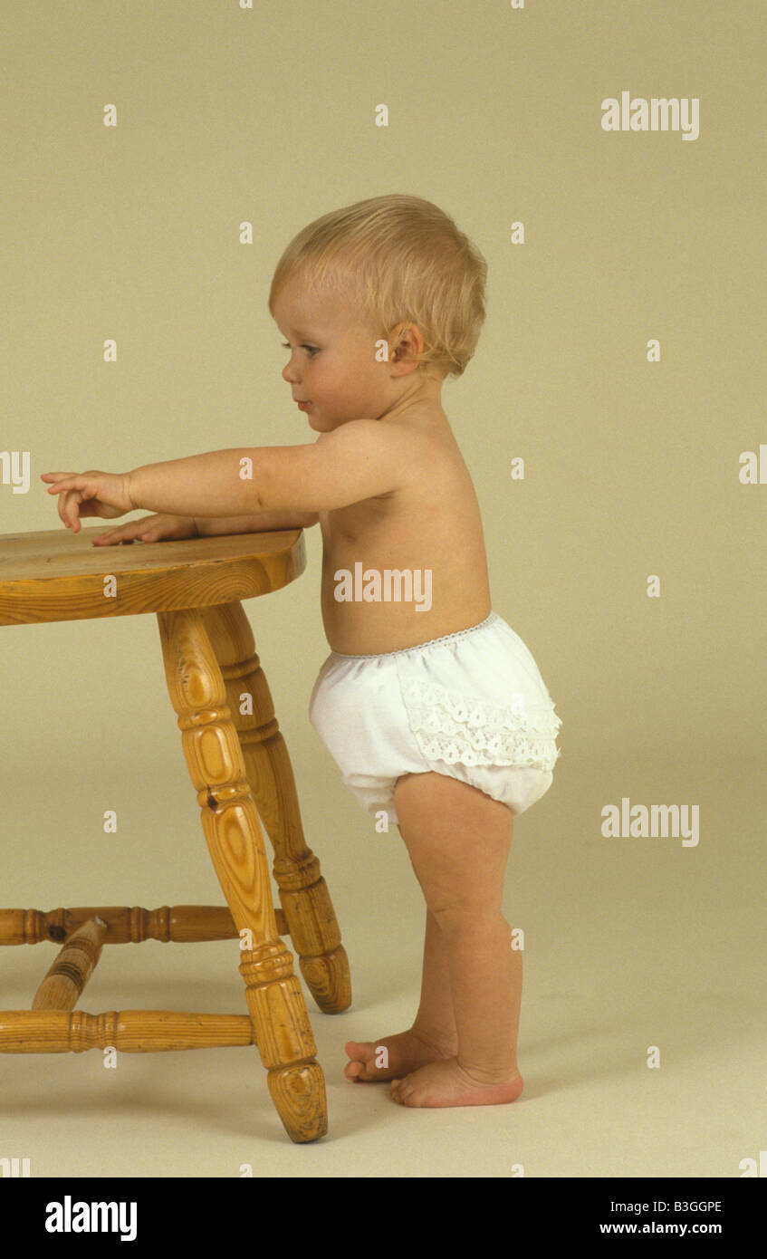 toddler pulling herself up onto a chair Stock Photo Alamy