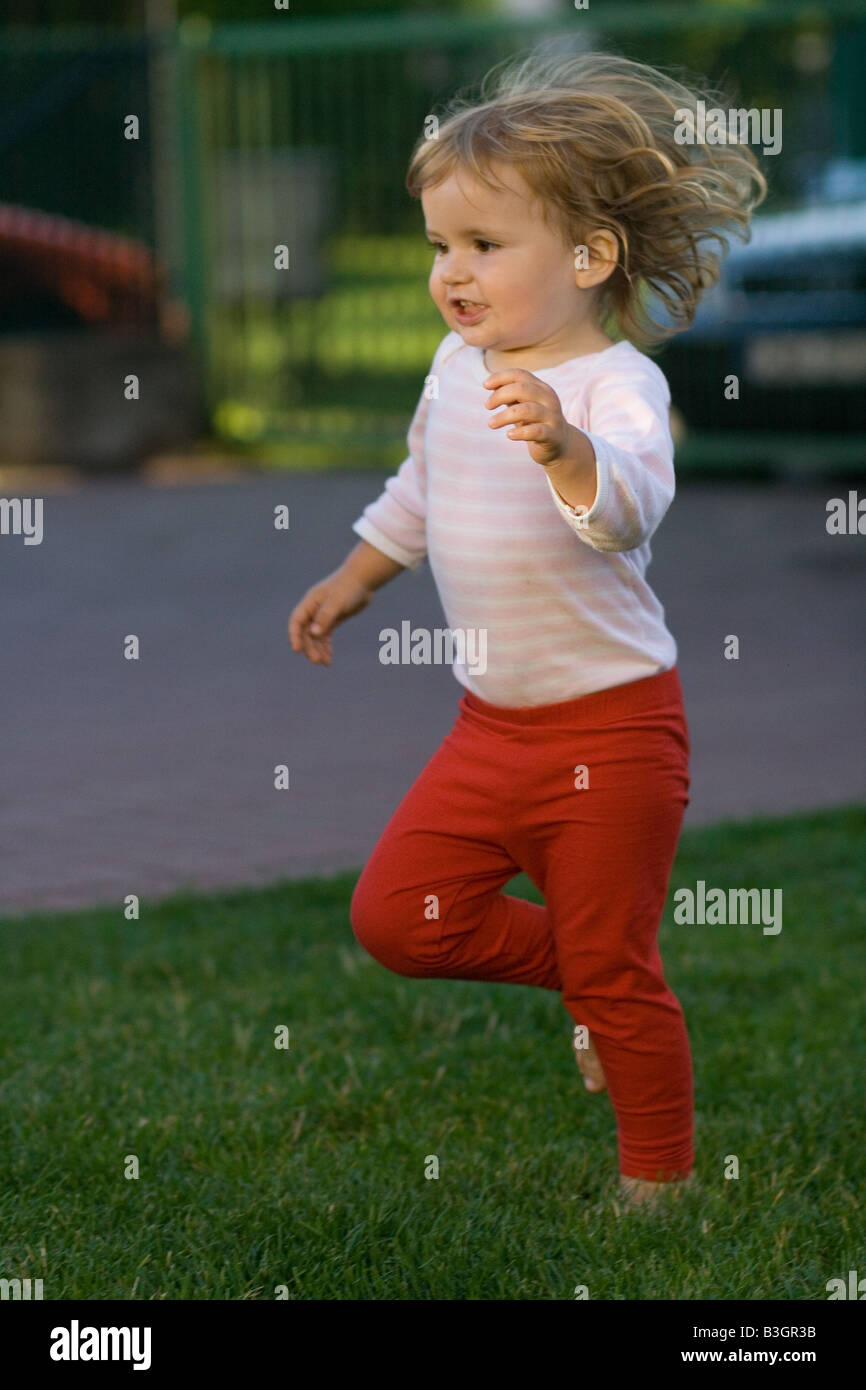 A portrait of two years old girl running on in the garden. Vivid colors
