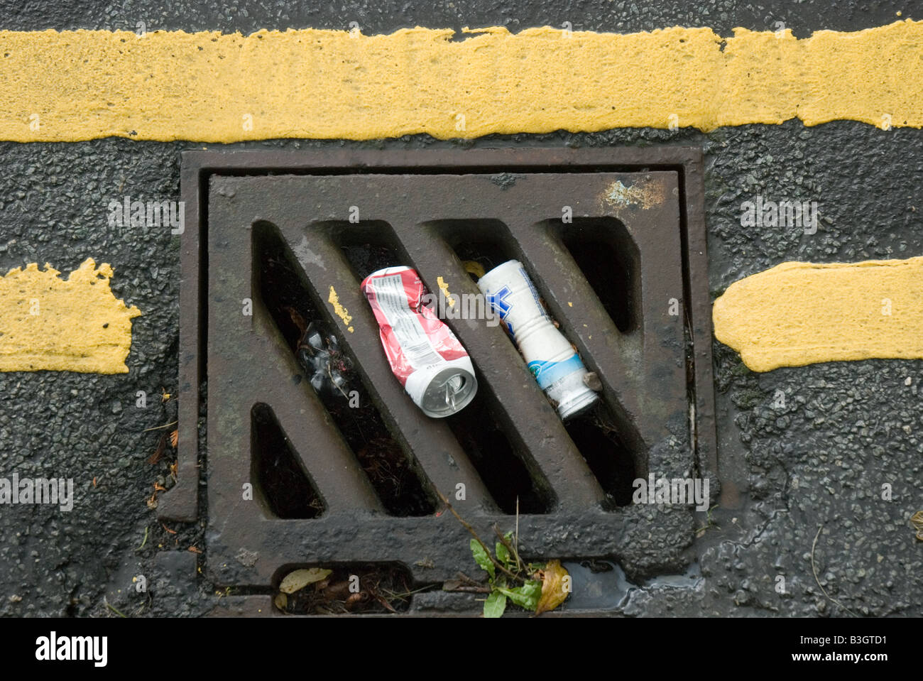 Street drainage cover with 2 tin cans Stock Photo Alamy