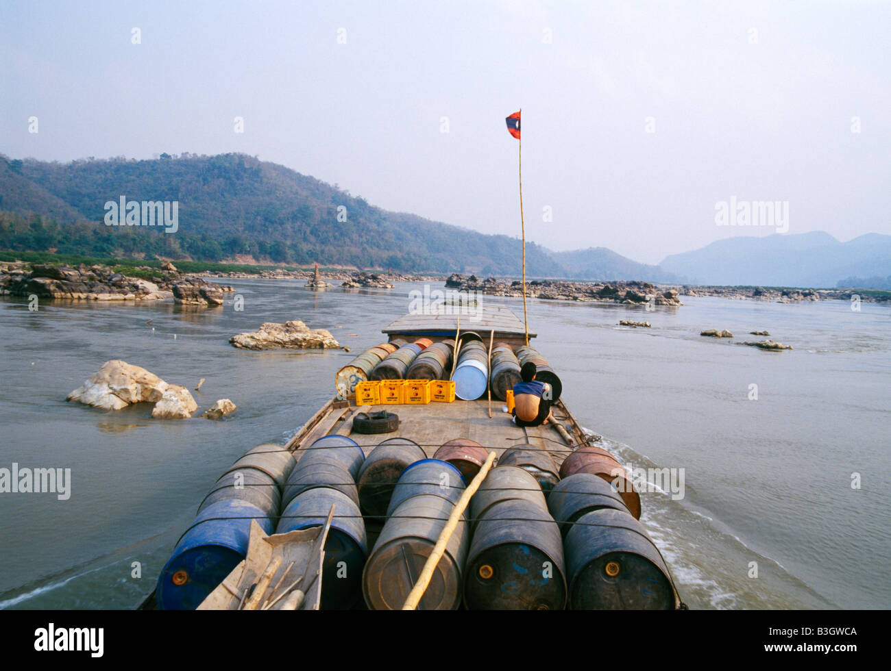 loaded frightboat is navigating between rock on the Mekong river during the dry season beladenes Frachtboot Stock Photo