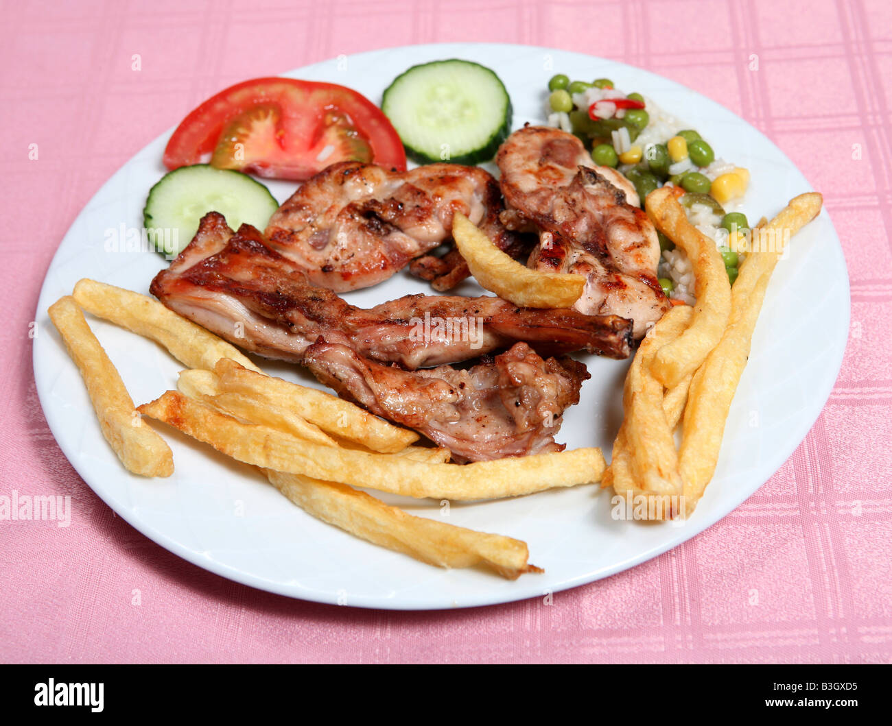 A grilled rabbit served with french fries rice and vegetables in a taverna restaurant Rabbit is a favourite meat for the Greeks Stock Photo