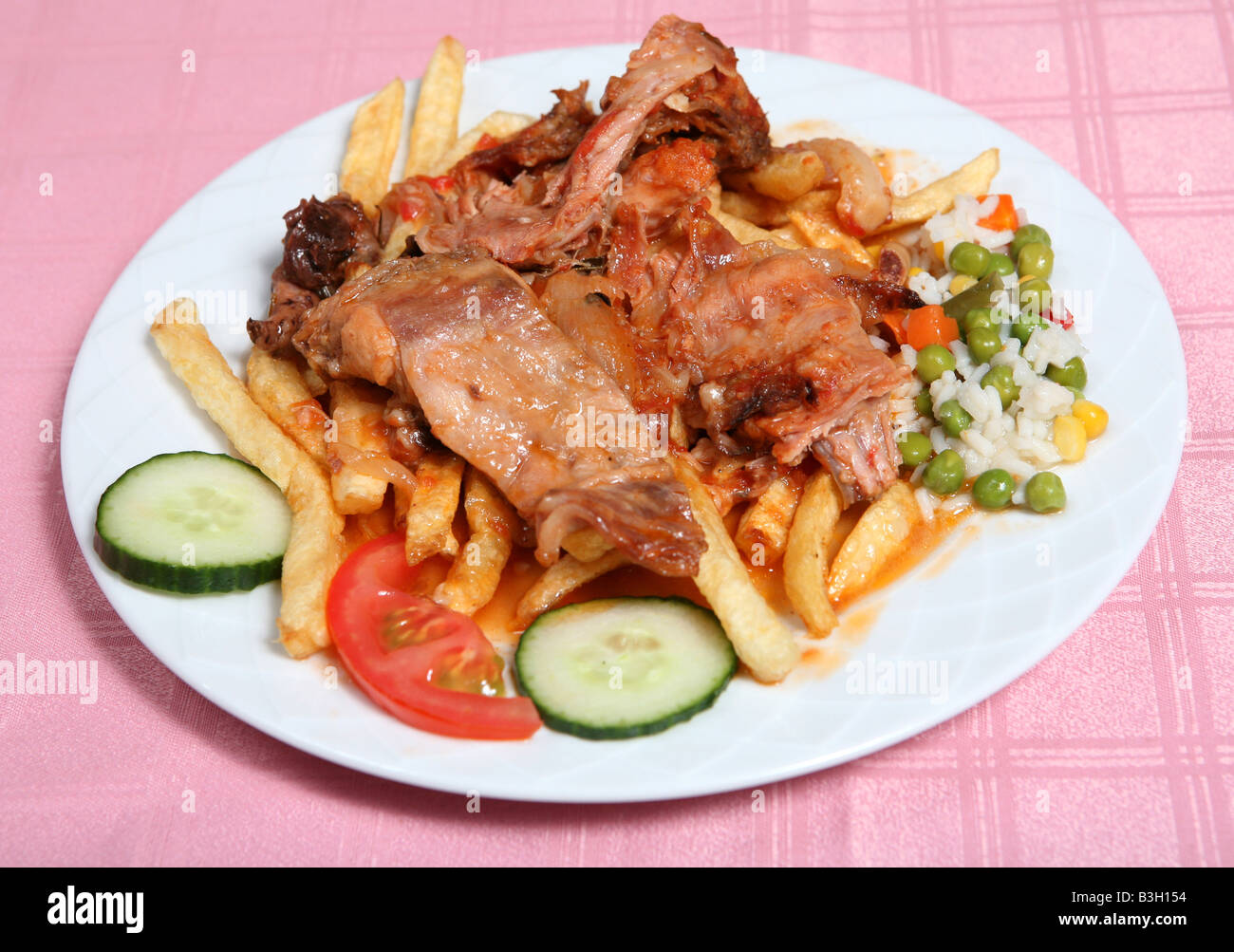 Traditional Greek rabbit stifado or stew at a taverna in Greece served with french fries rice and vegetables Stock Photo