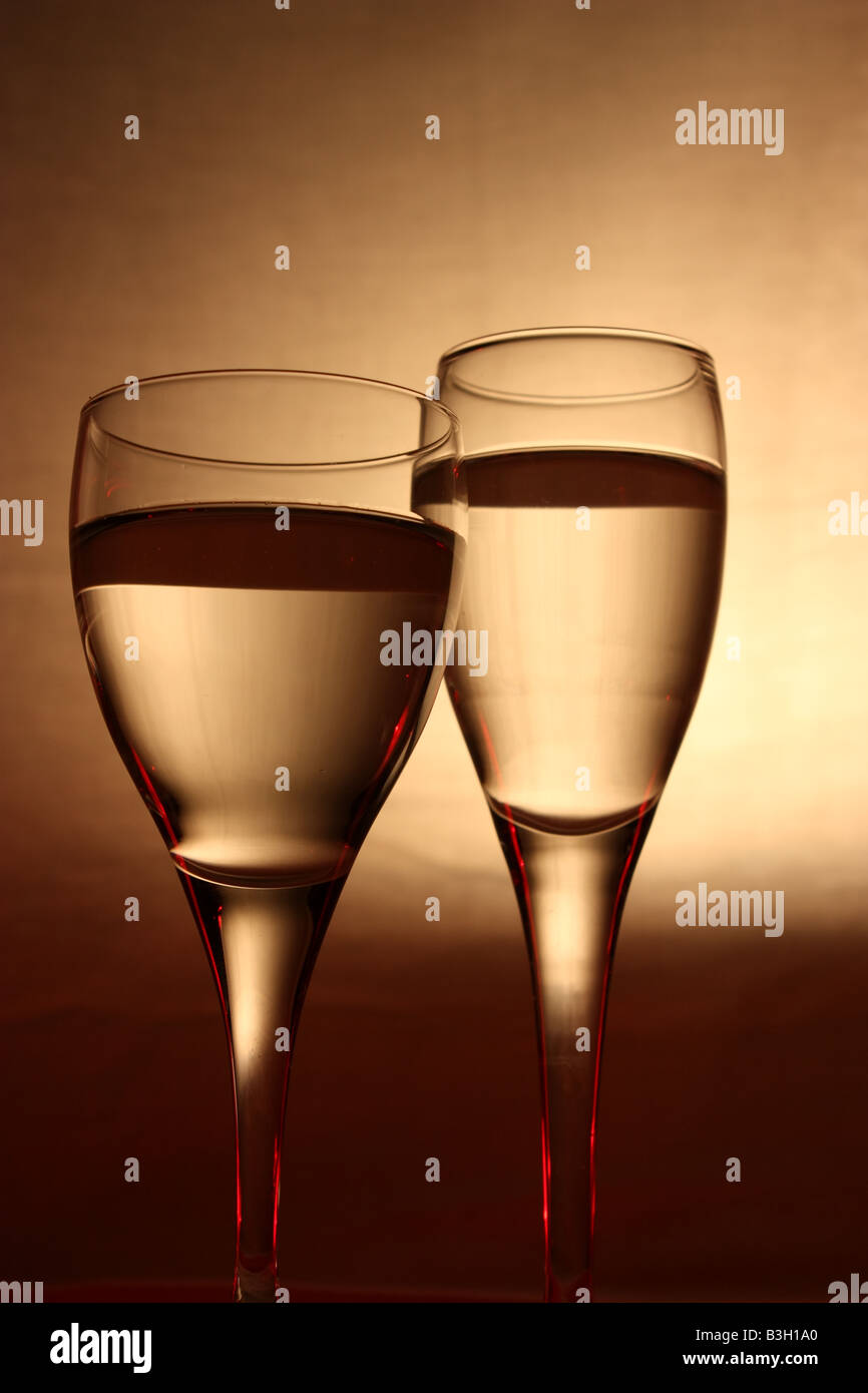 two different types of wine glasses filled with liquid and arranged on a timber box with a smooth glow foreground Stock Photo