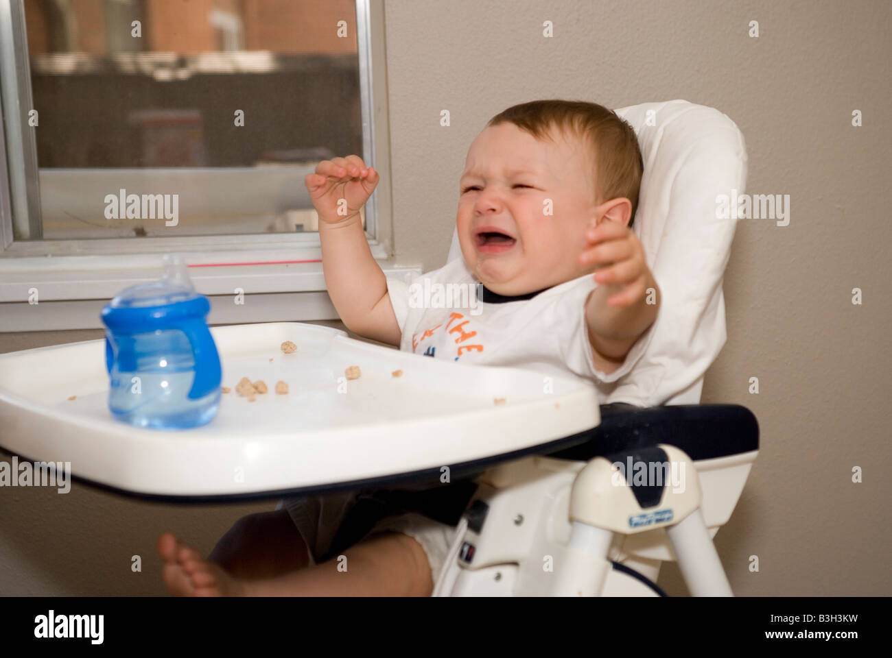 eight month old baby boy crying in his high chair at home Stock Photo