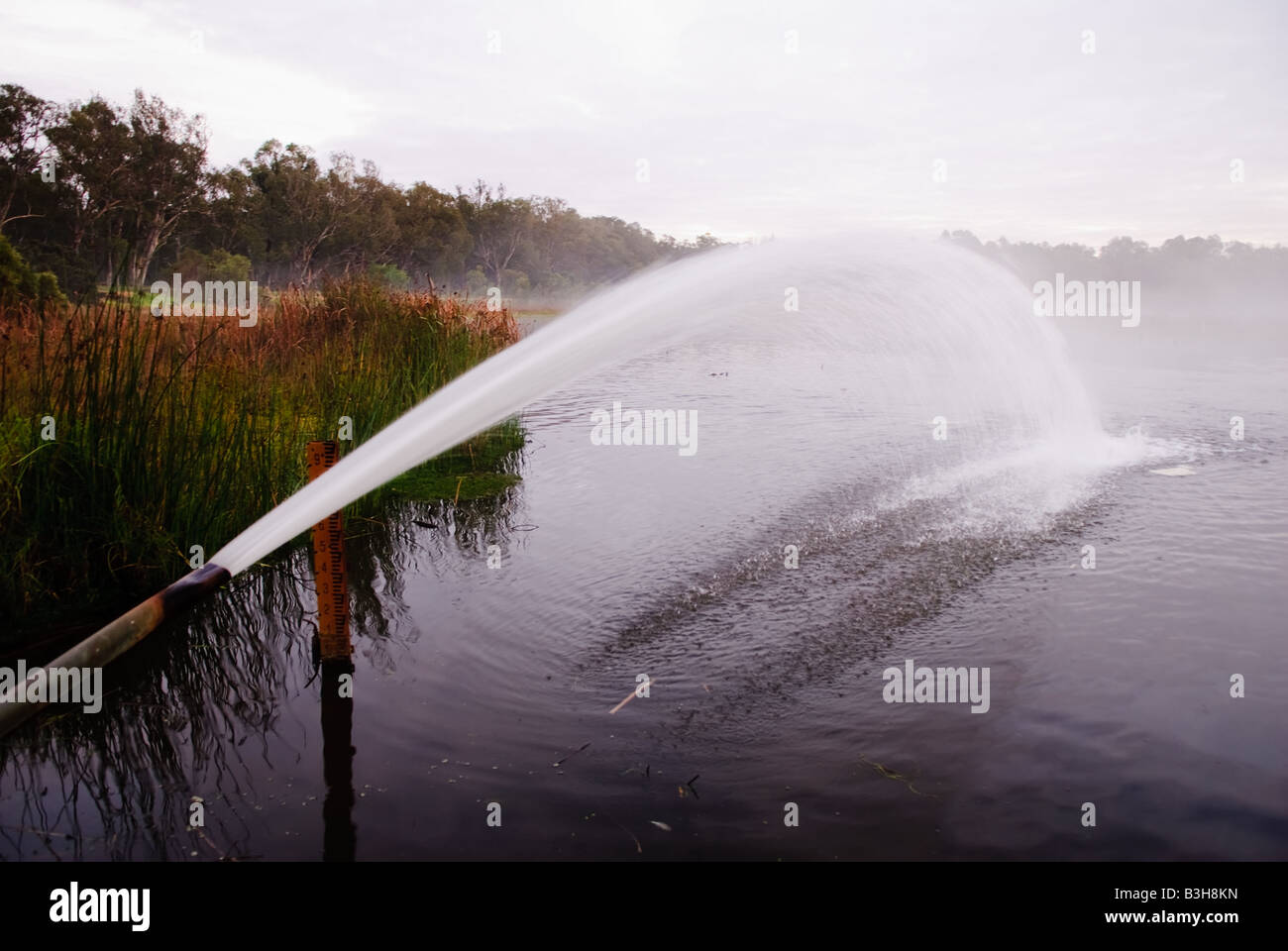 Water pipe throwing water into the air to aerate a man made lake in Western Australia Stock Photo