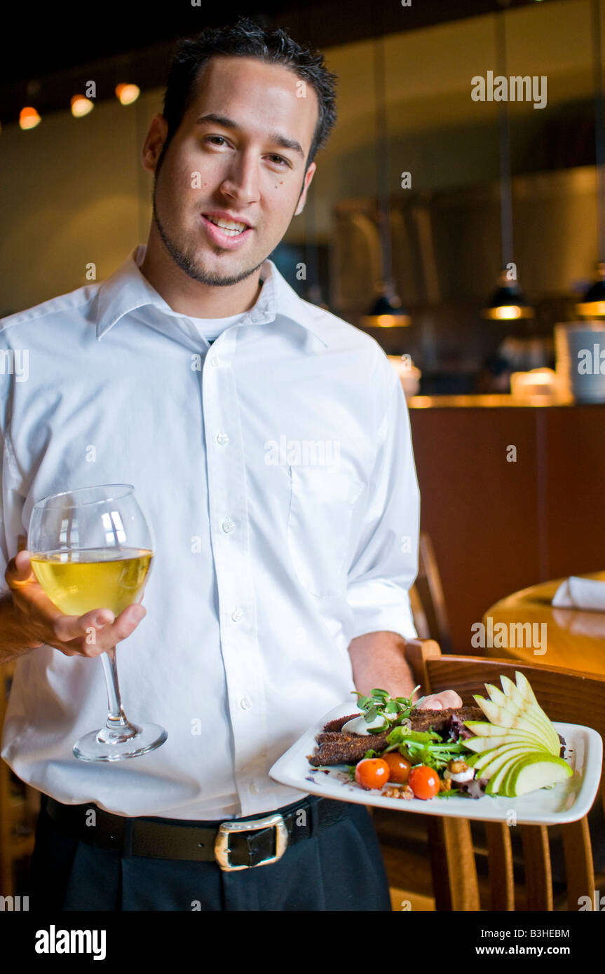 A waiter brings food and wine to people at a nice restaurant Stock