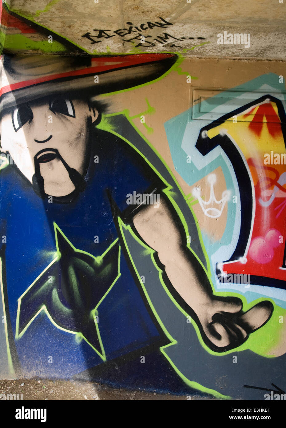 A graffiti image of a Mexican making a rude gesture painted on a wall. Stock Photo