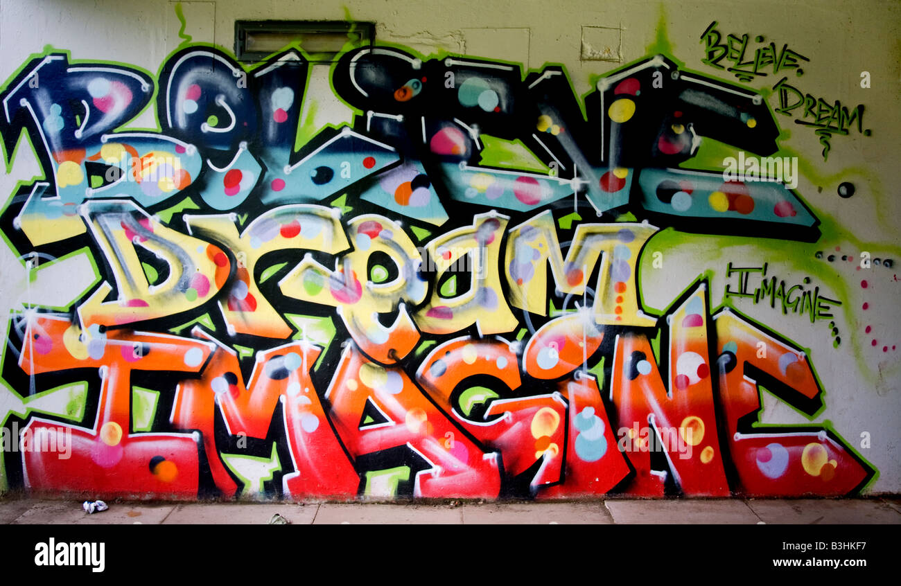 Graffiti words believe, dream, imagine, painted on an underpass wall. Stock Photo