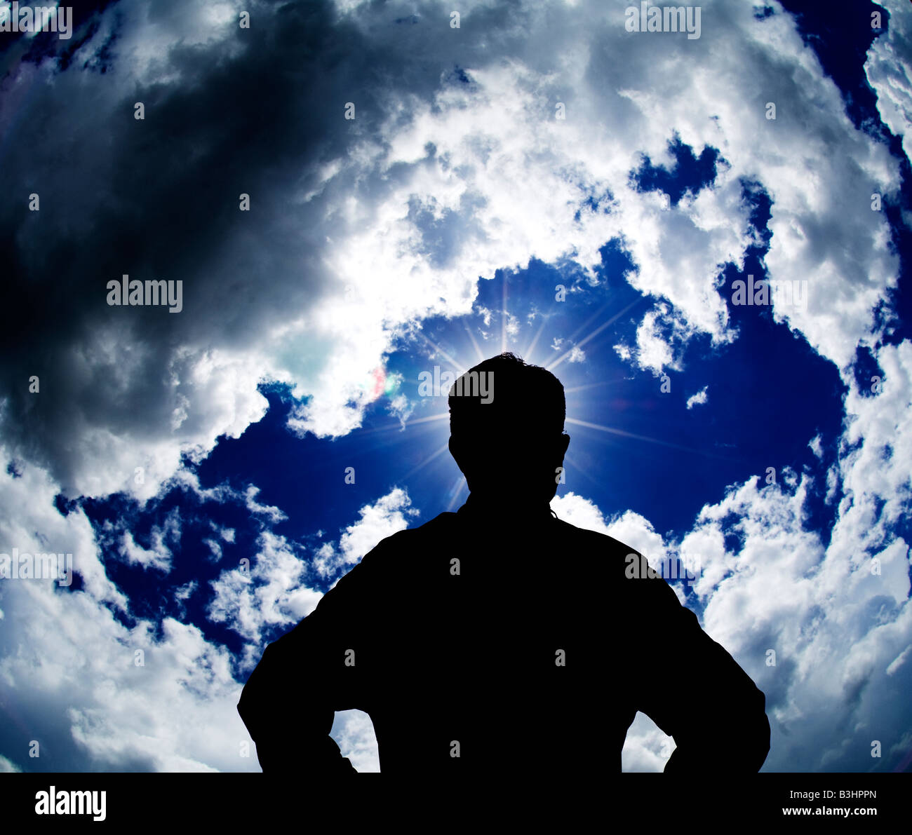 man looking at bright spot in stormy sky Stock Photo