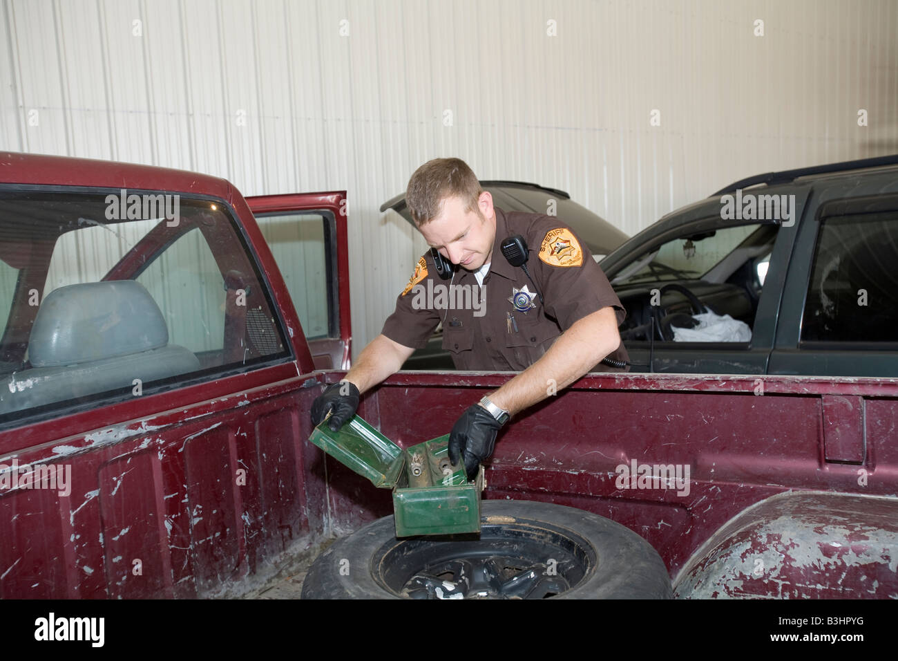 Deputy sheriff searching vehicle for drugs and other illegal items. Stock Photo
