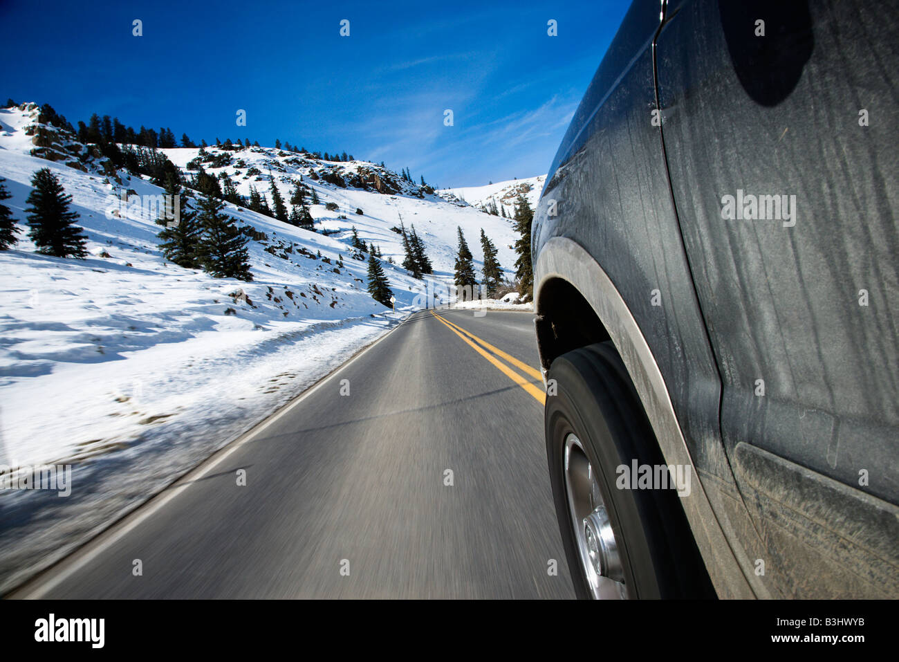 Perspective shot of SUV driving down road in snowy Colorado during winter Stock Photo