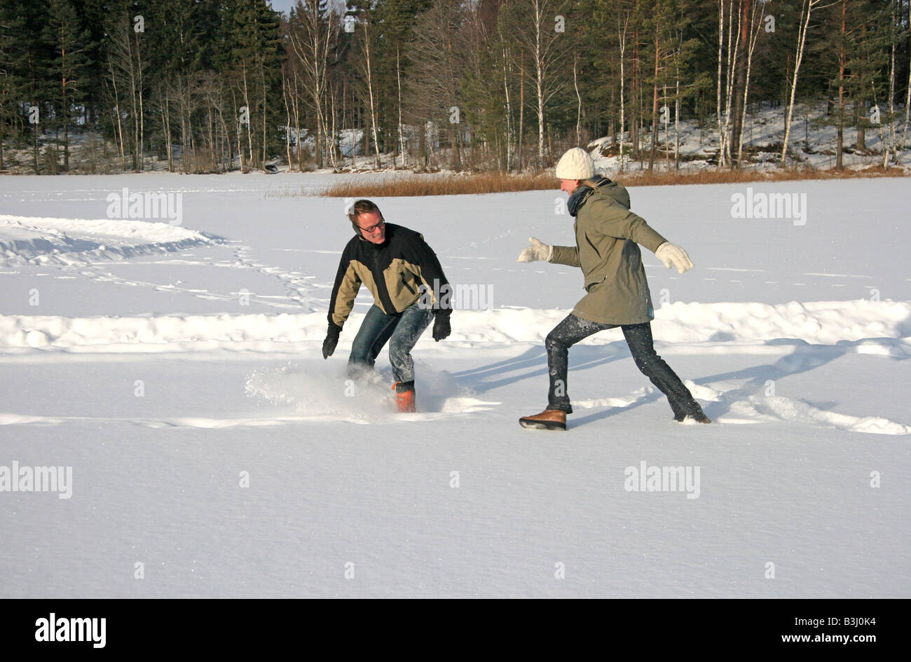 Young couple having fun playing in the snow Stock Photo - Alamy